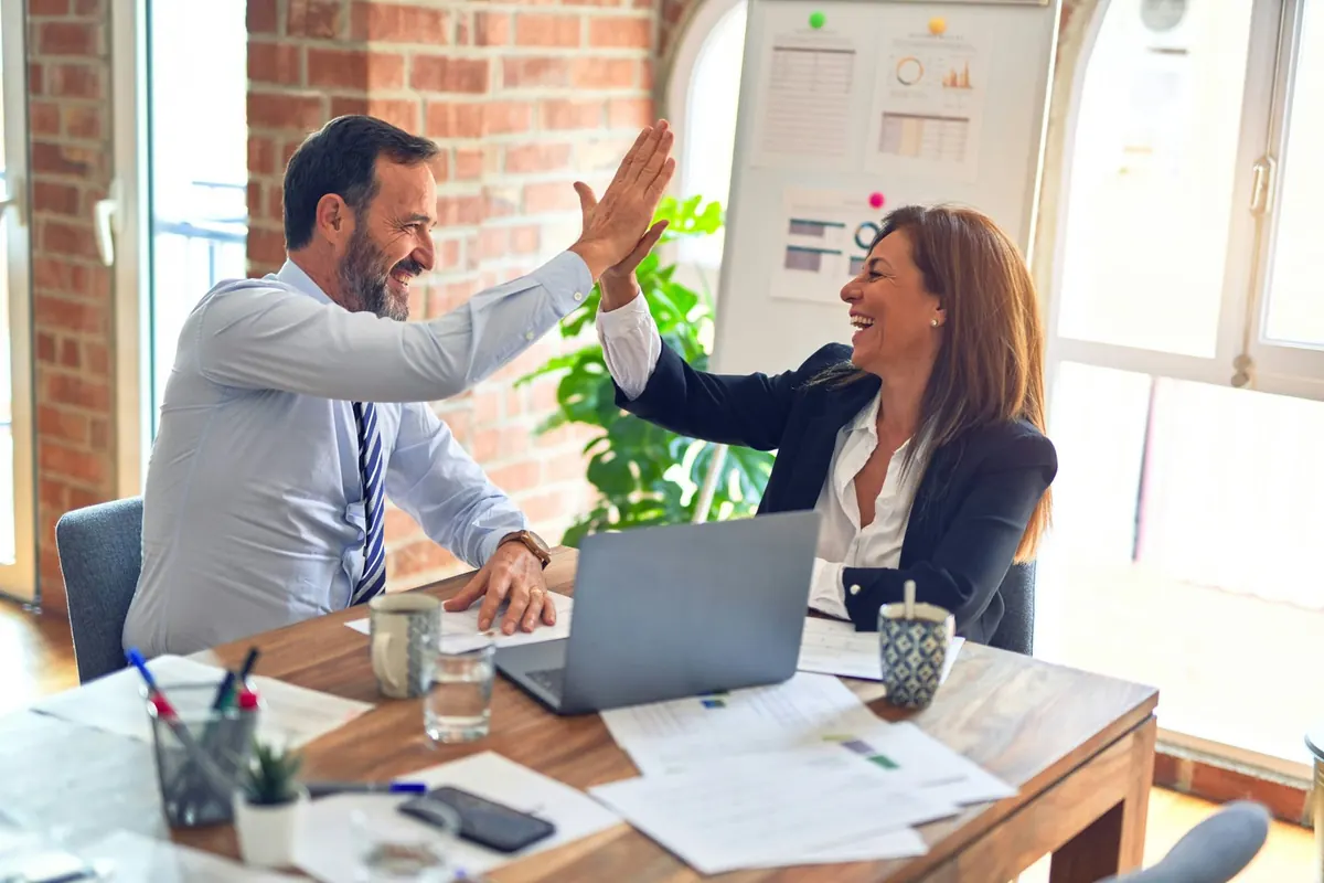 Dos profesionales celebran un acuerdo en una reunión de trabajo